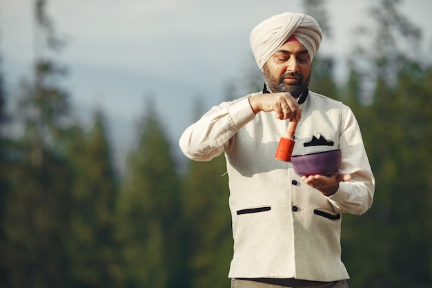 Indian man in a mountains. Male in a traditional turban. Hinduist with special things for rituals.