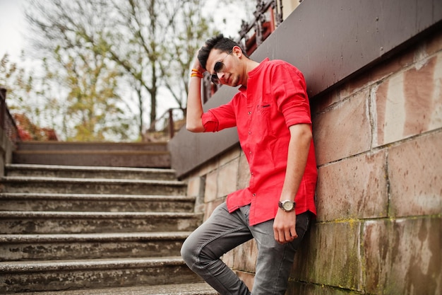 Indian man at red shirt and sunglasses posed outdoor