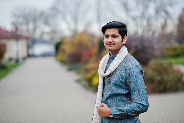 인도 남자는 야외 포즈를 취한 흰색 스카프로 전통 옷을 입습니다.