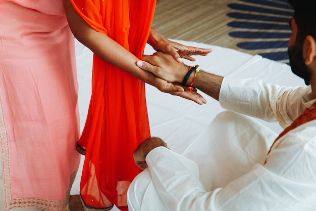 Indian Man in white attire and woman in salmon dress are holding hands