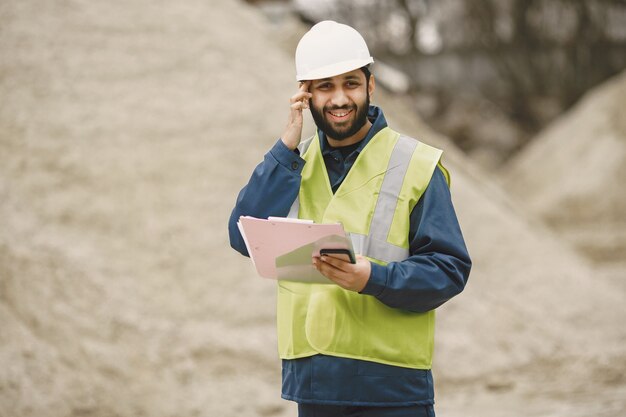 Indian man working. Male in a yellow vest. Man with folder.