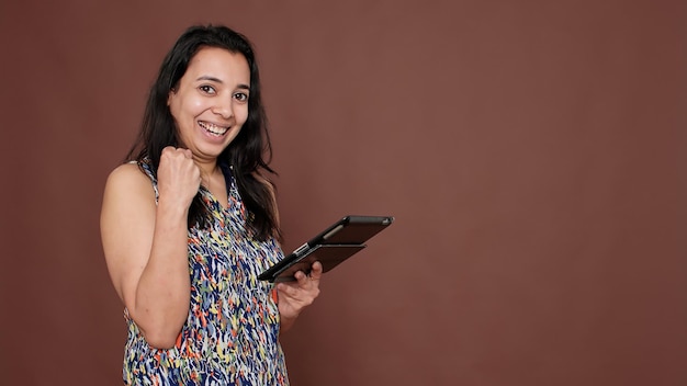 Persona indiana che usa la tavoletta digitale per raggiungere il successo, sentendosi orgogliosa mentre naviga attraverso l'app del sito web internet. dispositivo portatile con touchscreen per scorrere sui social network.