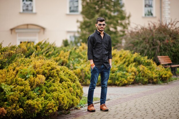 Indian stylish man at black shirt and sunglasses posed outdoor