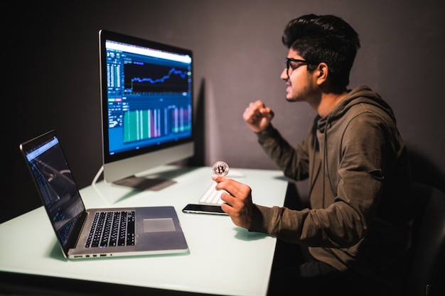 Indian trader with bitcoin checking stock trading data analysis concept working in office with financial graph on computer monitors