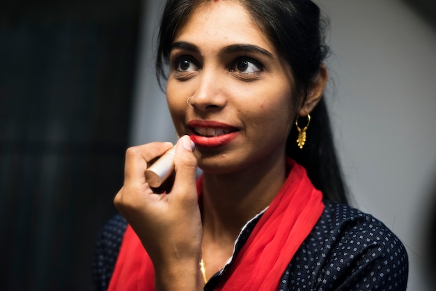 Indian woman putting on a lipstick