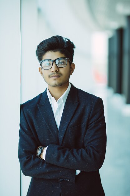 近代的なオフィスに立っているインドの青年実業家