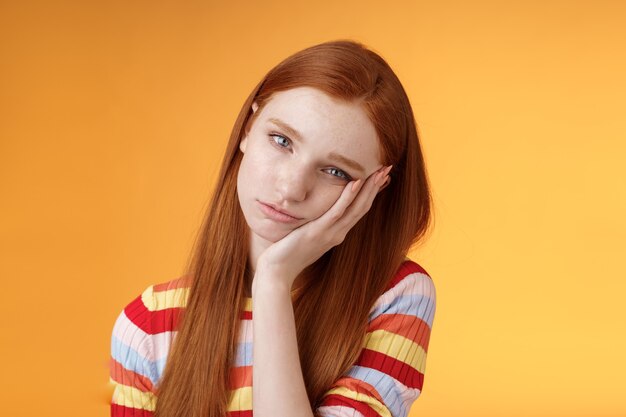 Indifferent careless sleepy redhead silly female student lean palm looking bored uninterested listen lame stories wanna escape standing exhausted lacking interest, posing orange background