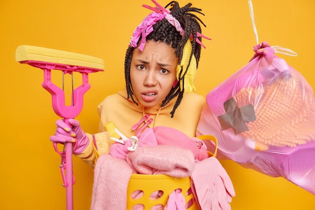 Indignant African American woman has dreadlocks poses with garbage