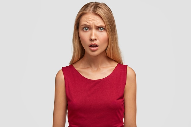 Free photo indignant displeased blonde woman model with sullen expression, frowns face and opens mouth in displeasure