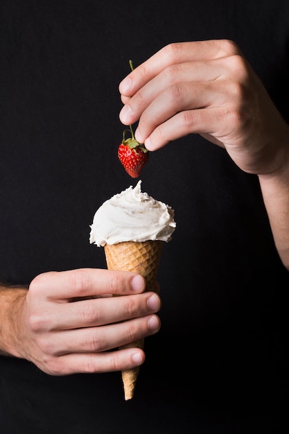 Free photo individual holding ice cream scoop with strawberry