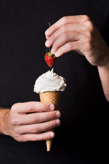 Individual holding ice cream scoop with strawberry