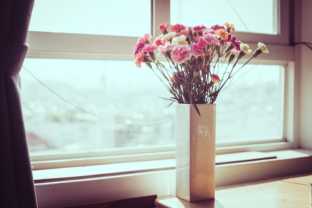 Free photo indoor flower on the windowsill. white vase, pot. curtains, tulle