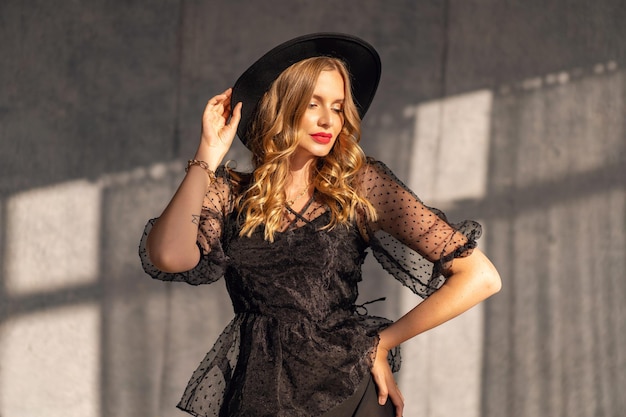 Indoor luxuey fashion portrait of elegant woman wearing black evening dress and hat elegant and stylish