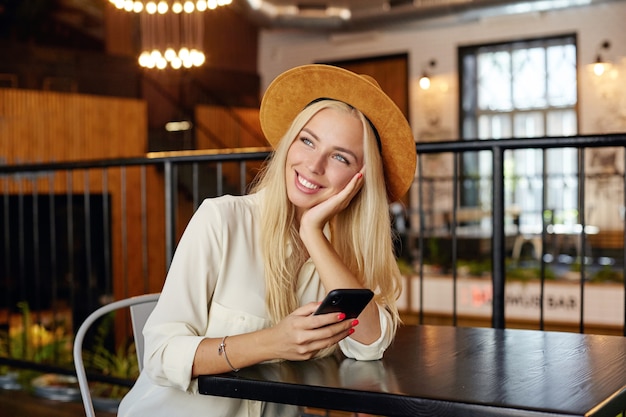 indoor-photo-charming-young-blonde-female-white-shirt-brown-hat-sitting-cafe-interior-leaning-head-her-palm-looking-dreamily-aside_295783-5211.jpg