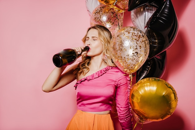 Indoor photo of european woman with blonde hair drinking wine