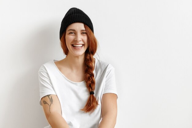 Indoor portrait of attractive redhead European hipster student girl wearing white t-shirt