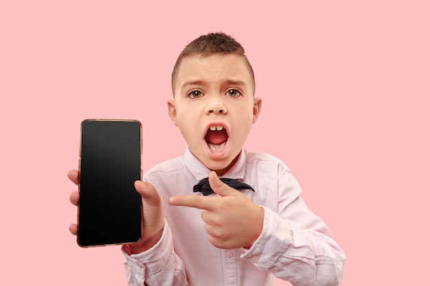 Indoor portrait of attractive young boy holding blank smartphone