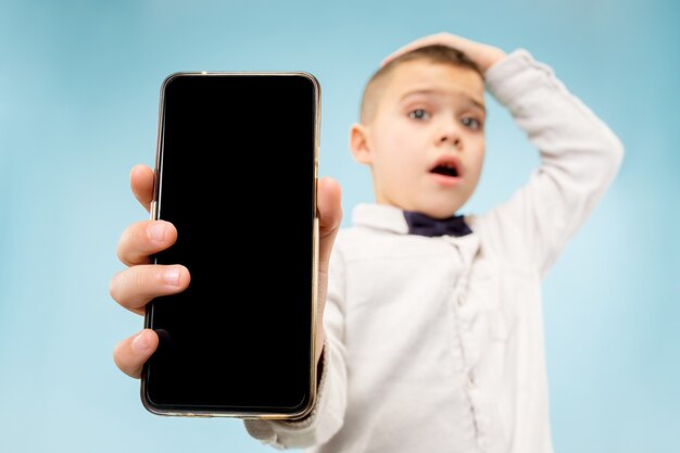 Indoor portrait of attractive young boy holding blank smartphone