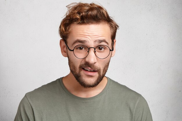 Indoor portrait of bearded young man with trendy hairstyle