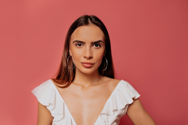 indoor portrait of beautiful pretty woman wearing white t-shirt posing during photoshoot over pink wall