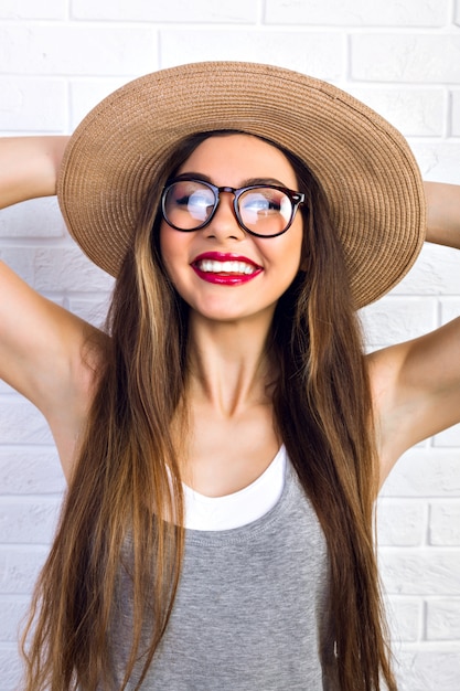 Foto gratuita ritratto dell'interno della donna graziosa dolce e carina che indossa occhiali e cappello di paglia, pronta per le vacanze estive, emozioni positive, gioia, divertimento.