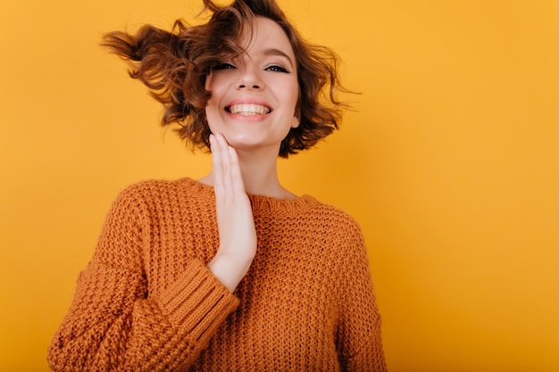 Indoor portrait of easygoing young woman expressing happiness