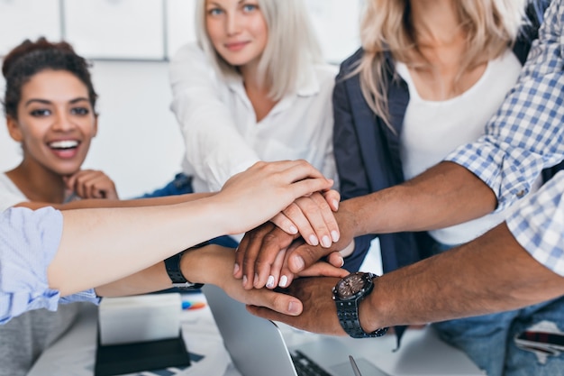 Indoor portrait of joyful african woman with shaking hands. Stylish businesswoman with elegant manicure made a deal with young partners in office.