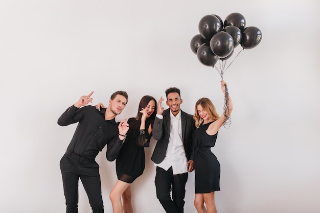 Indoor portrait of laughing young people came with balloons to make surprise for birthday woman