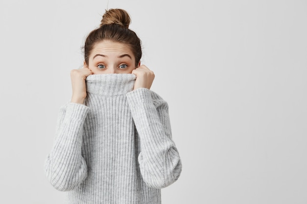 楽しいジャンパーから覗く素敵な女性の屋内ポートレート。見つけたくない服の女の子の下からとんでもない女性の表情。ボディランゲージ