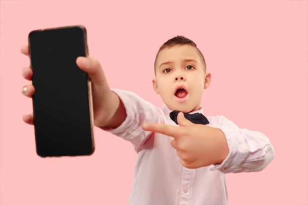 Бесплатное фото Крытый портрет привлекательного мальчика, держащего пустой смартфон