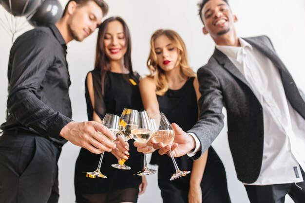 Indoor portrait of people clink glasses with guys in black attires