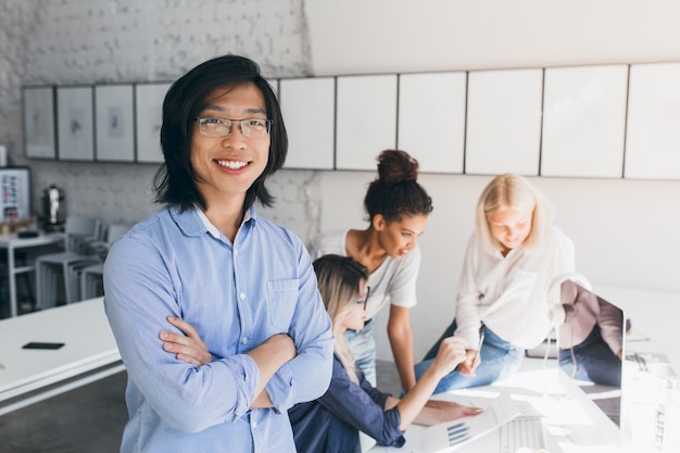 Free photo indoor portrait of successful asian it-specialist standing with arms crossed and smiling