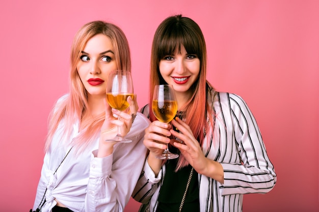 Indoor  portrait of two happy best friends sisters women, wearing trendy black and white clothes, sue prized face