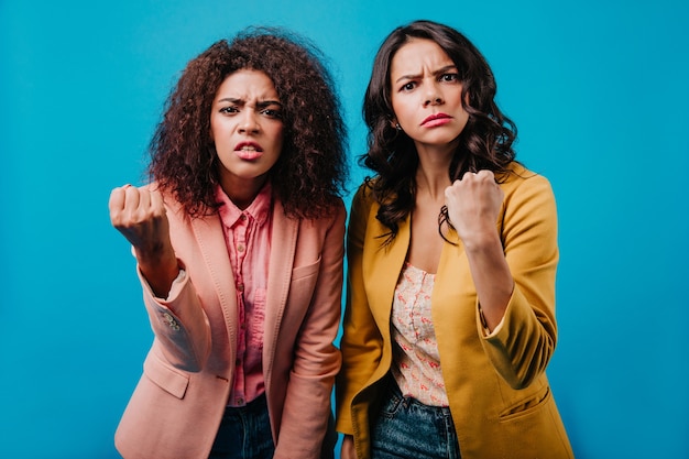 Indoor portrait of two women waving their fists