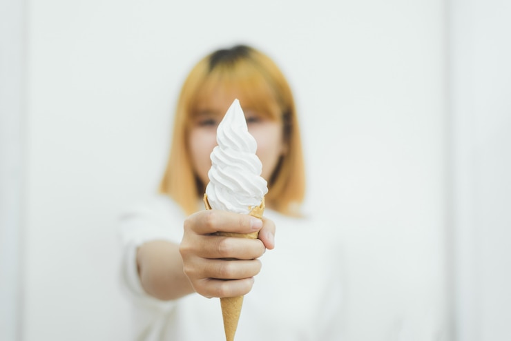 無料Photo 夏にアイスクリームを食べる若い美しいアジアの女性の屋内の肖像画