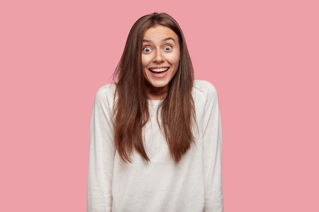 Indoor shot of amazed young Caucasian woman with shocked surprised expression