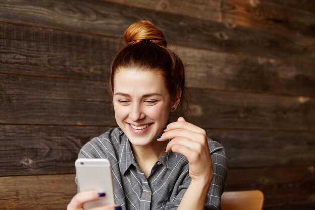 Indoor shot of attractive young female using video conferencing app on mobile phone