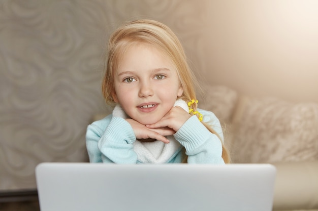Indoor shot of beautiful Caucasian blonde female kid with messy hairstyle