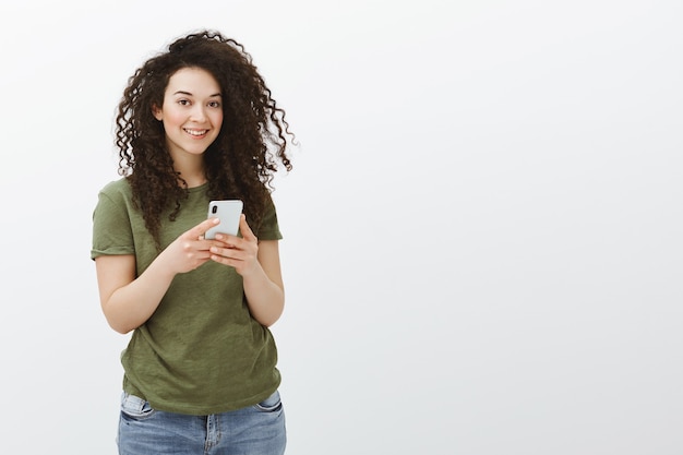 Indoor shot of charming flirty curly-haired female employee in casual t-shirt