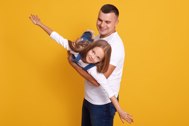 Indoor shot of cheerful awesome man lifting his kid