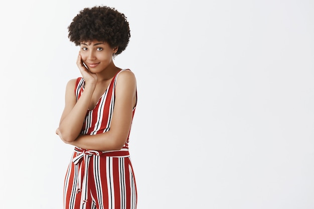 Free photo indoor shot of cute and tender african american woman with afro hairstyle leaning head on hand and gazing with gentle and loving expression