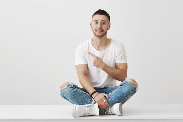 Free photo indoor shot of embarrassed young guy with glasses posing