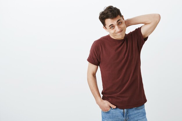 Indoor shot of guilty embarrassed european male model in casual red t-shirt