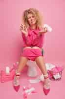 무료 사진 불쾌한 곱슬머리 젊은 여성이 생리대를 들고 있는 실내 사진과 탐폰은 월경 기간 동안 몸이 좋지 않은 핑크색 블라우스 바지를 신는다