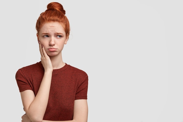 Free photo indoor shot of offended teenager purses lips, looks with dejected expression aside