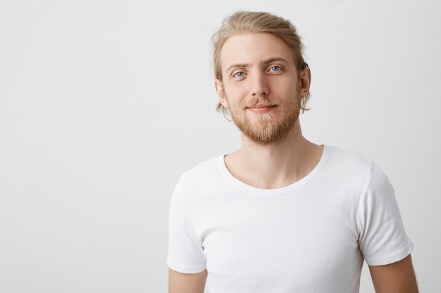 Free photo indoor shot of positive good-looking caucasian blond man with beard and moustache smirking