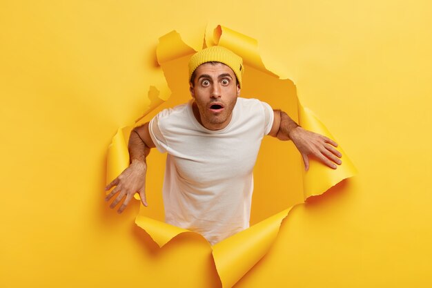 Indoor shot of puzzled shocked man looks in terror, being shocked by something