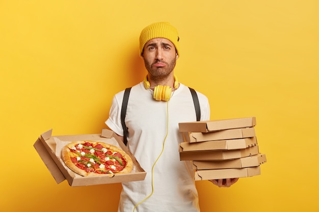 Free photo indoor shot of sad deliveryman with pizza boxes