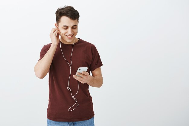 Indoor shot of satisfied carefree good-looking guy in casual red t-shirt