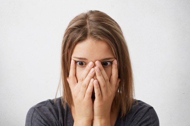 Free Photo indoor shot of shocked, scared or frustrated young woman covering face with hands, her eyes full of terror and panic
